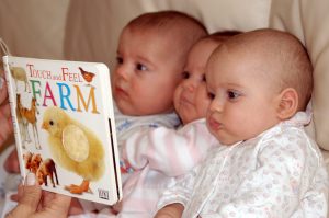 Mother reading to her triplets through ASL
